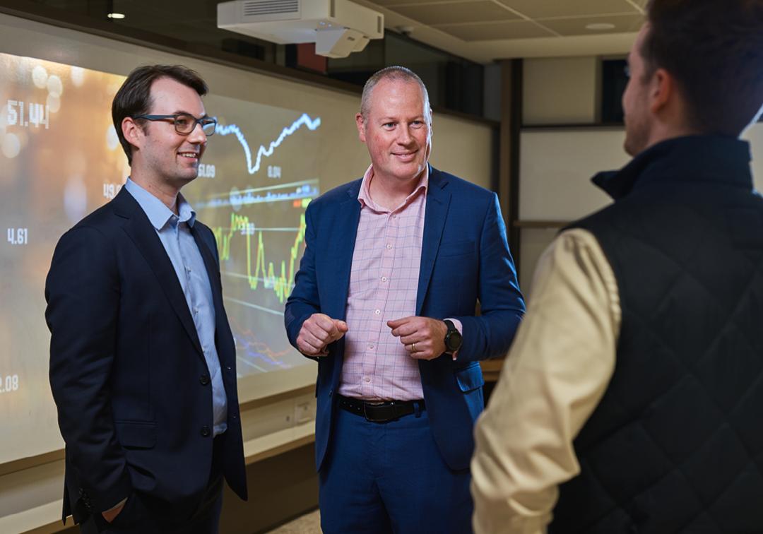 UQ finance teaching staff and students chat in a classroom