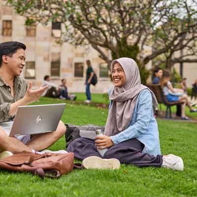 2 students sit on the grass in conversation