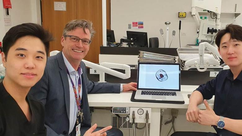 Sean and Ryan Choi sit in a lab with Prof Ove Peters, pointing at a laptop screen