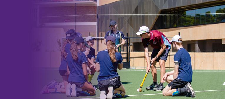 Health and physical education teacher demonstrating how to play hockey to high school students