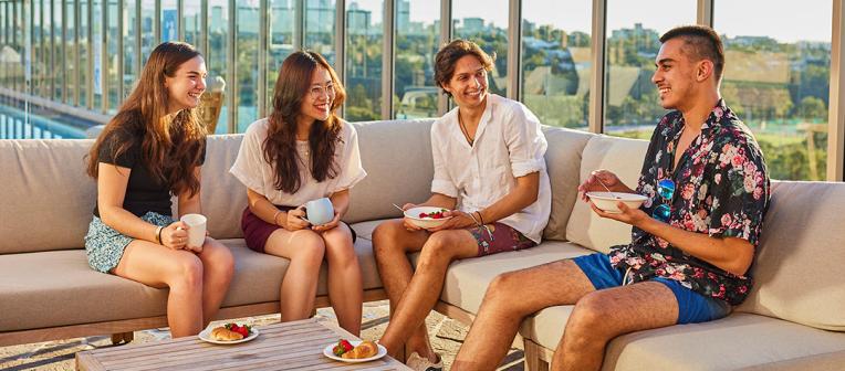 Four students socialising on the rooftop of Kev Carmody House