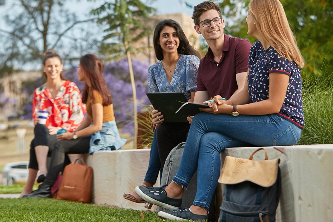 Students sitting on sandstone wall