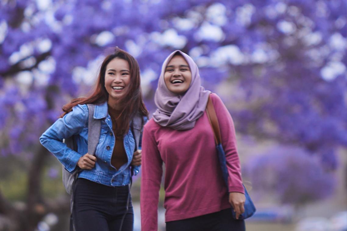 Students standing in front of flowering jacaranda tree
